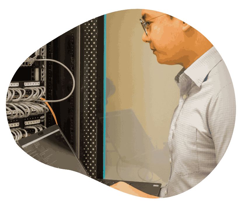 A man in a shirt and tie examines a server, showcasing a professional tech environment.