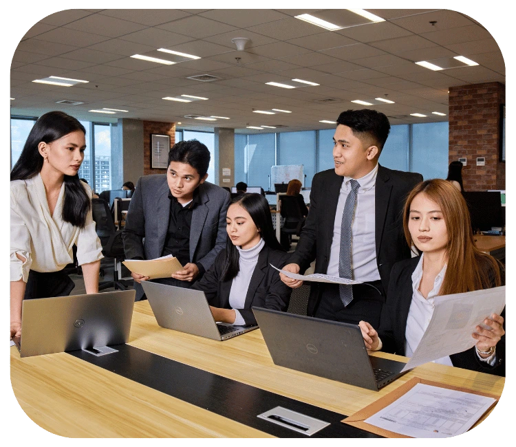 TRT Employees in an office setting, working together on laptops, showcasing teamwork and productivity.