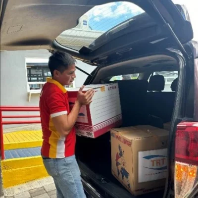 MCC officer loading TRT boxes into a car trunk, readying for a corporate boutique shipment.